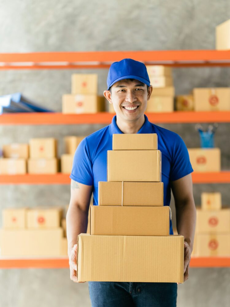 An Asian delivery man is working inside a warehouse. Delivery and service concept